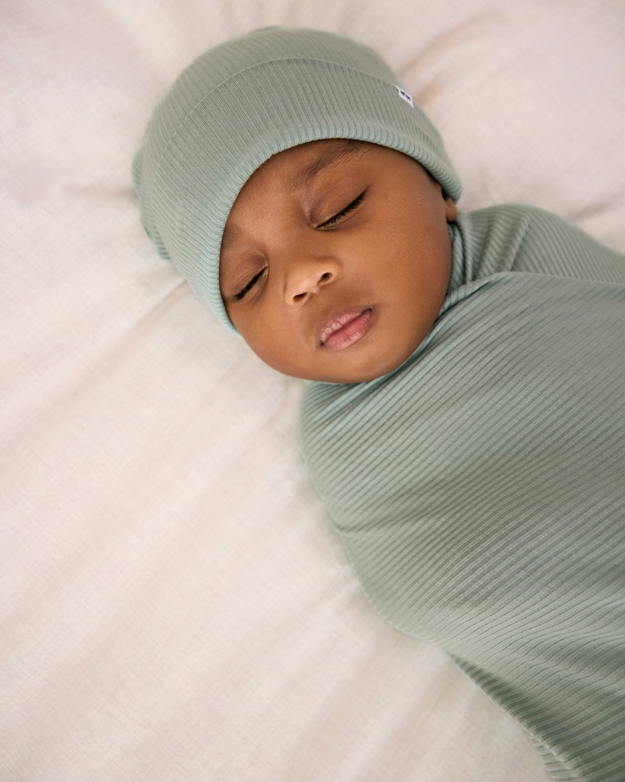 Alternate close up of newborn swaddled in the Willow Baby Ribbed Swaddle & Infant Beanie Set