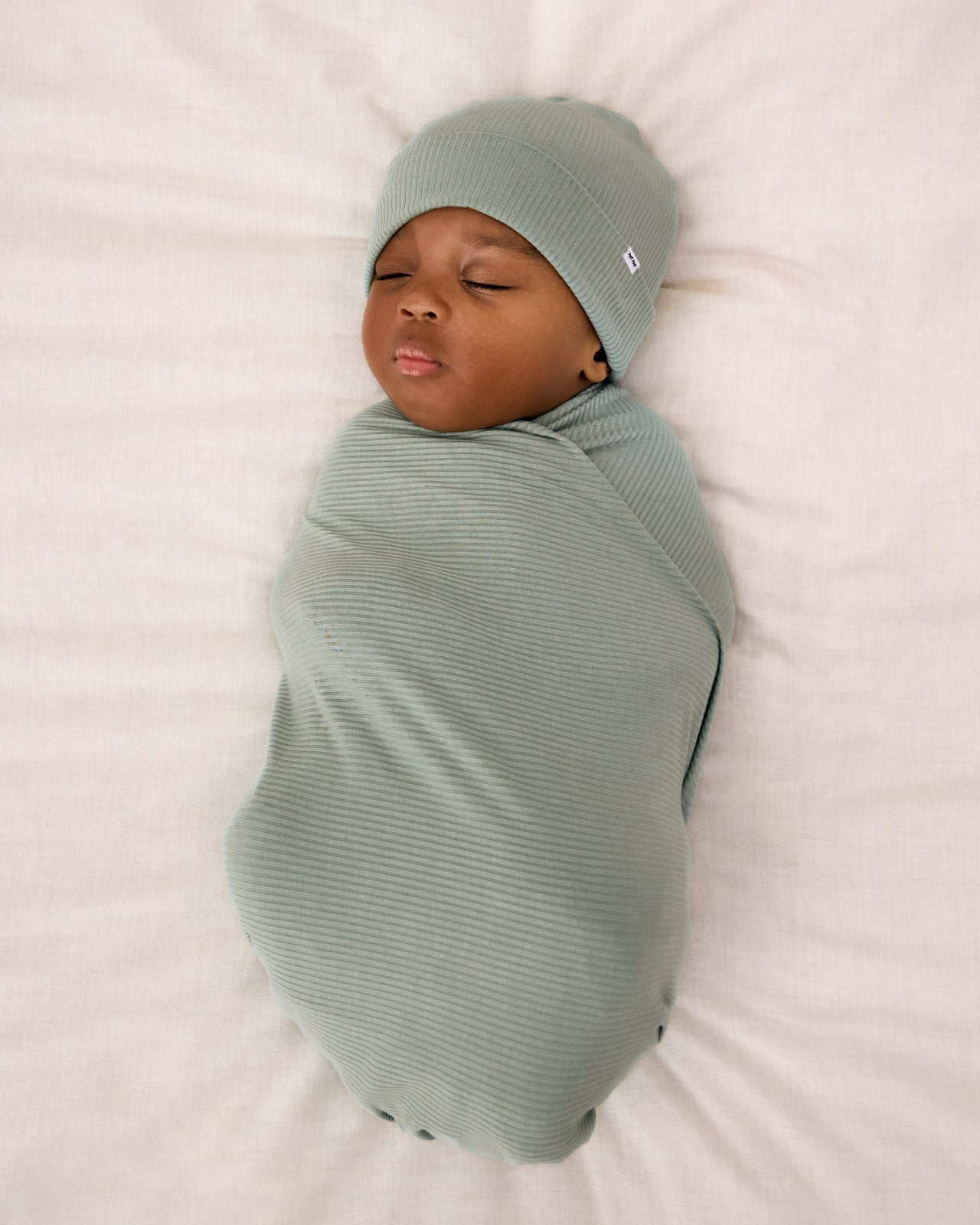 Aerial view of newborn swaddle in the Willow Baby Ribbed Swaddle & Infant Beanie Set