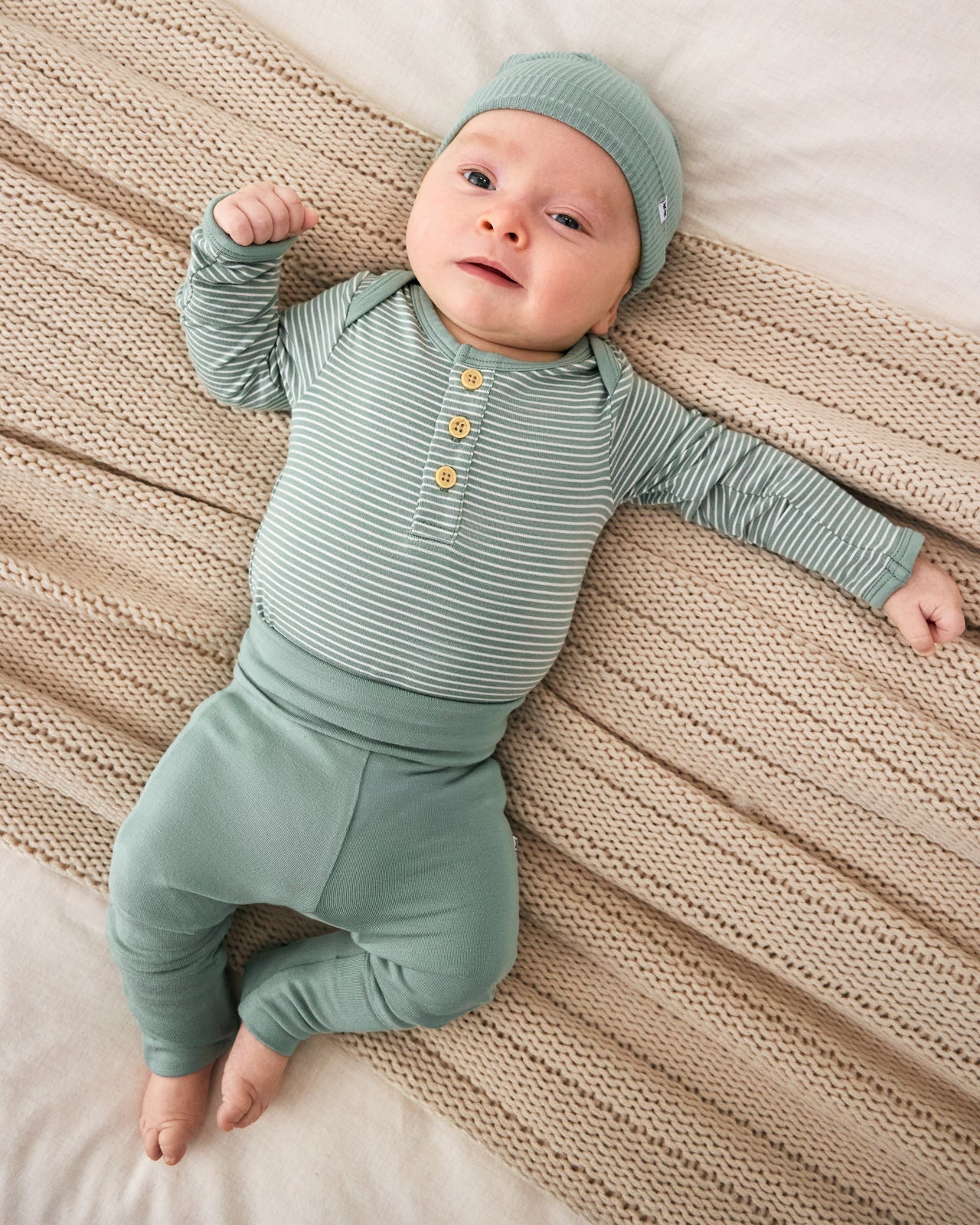 Aerial view of newborn wearing the Willow Stripe Henley Bodysuit with matching green leggings