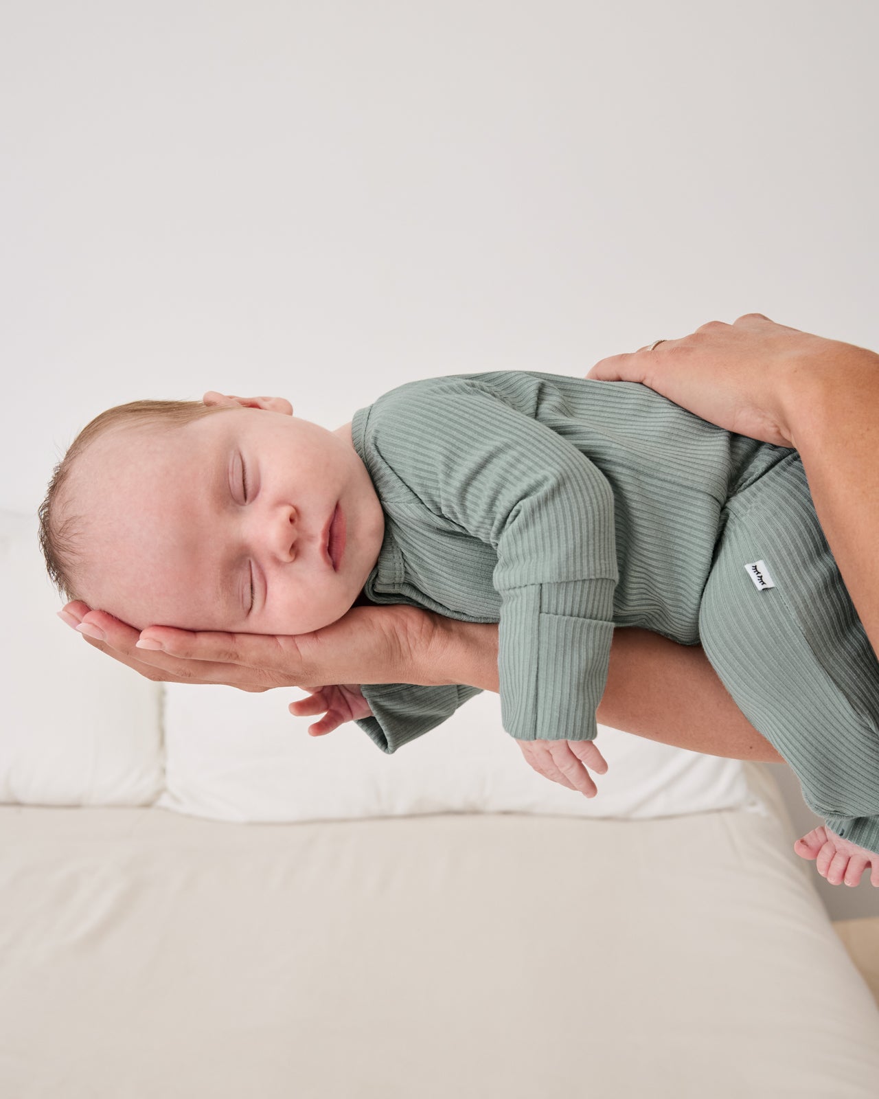 Adult holding sleeping newborn wearing the Willow Ribbed Zippy