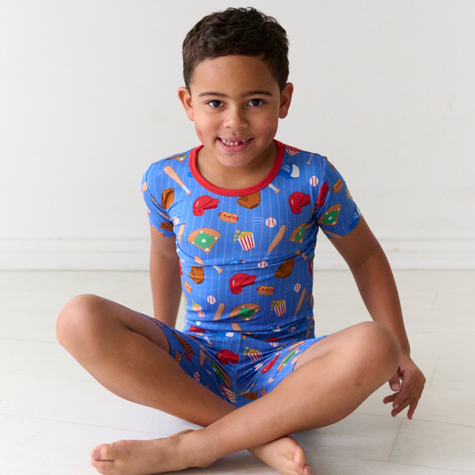 Child sitting wearing Blue All Stars two piece short sleeve and shorts bamboo pajama set