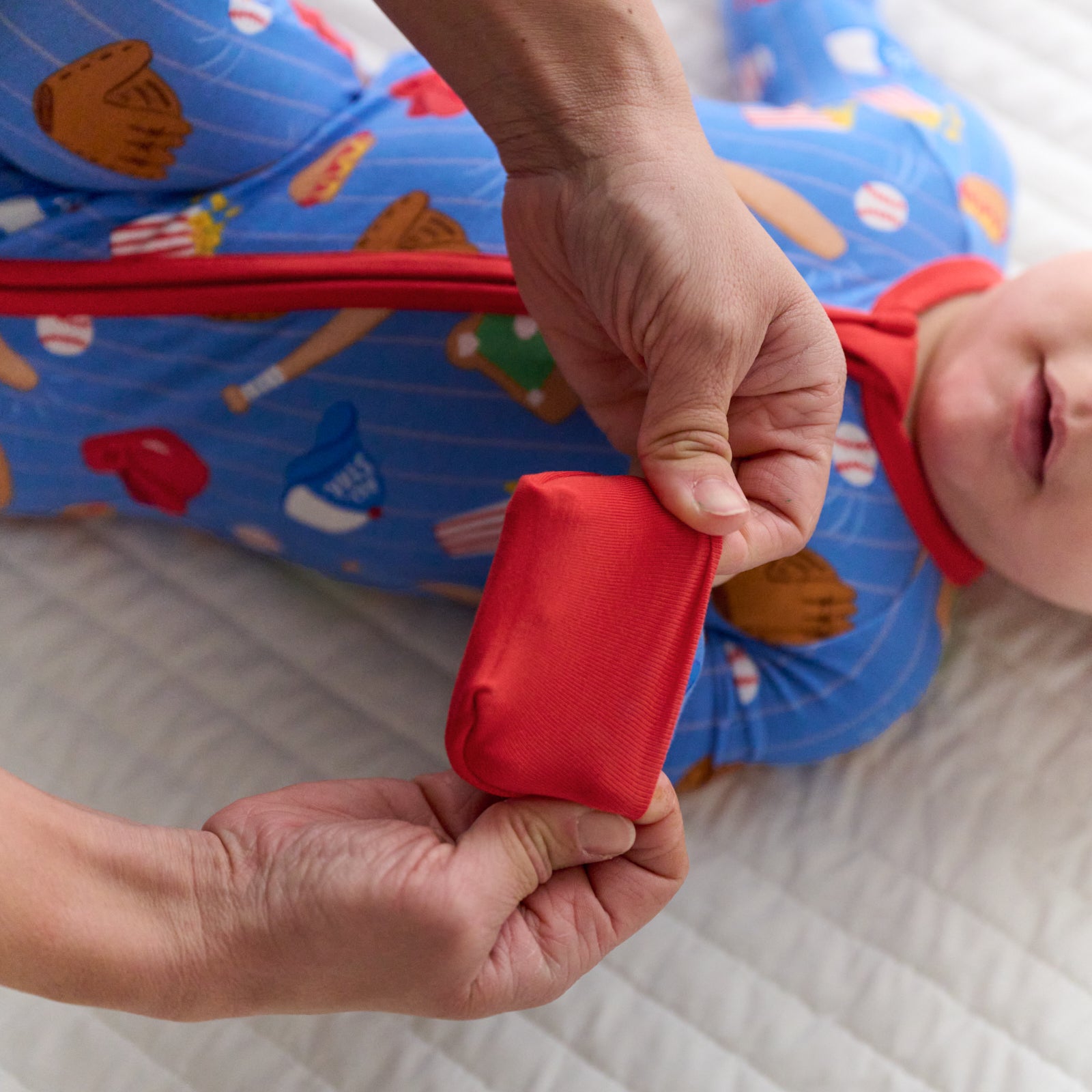 Parent folding over the convertible mitten on a Blue All Stars bamboo zippy