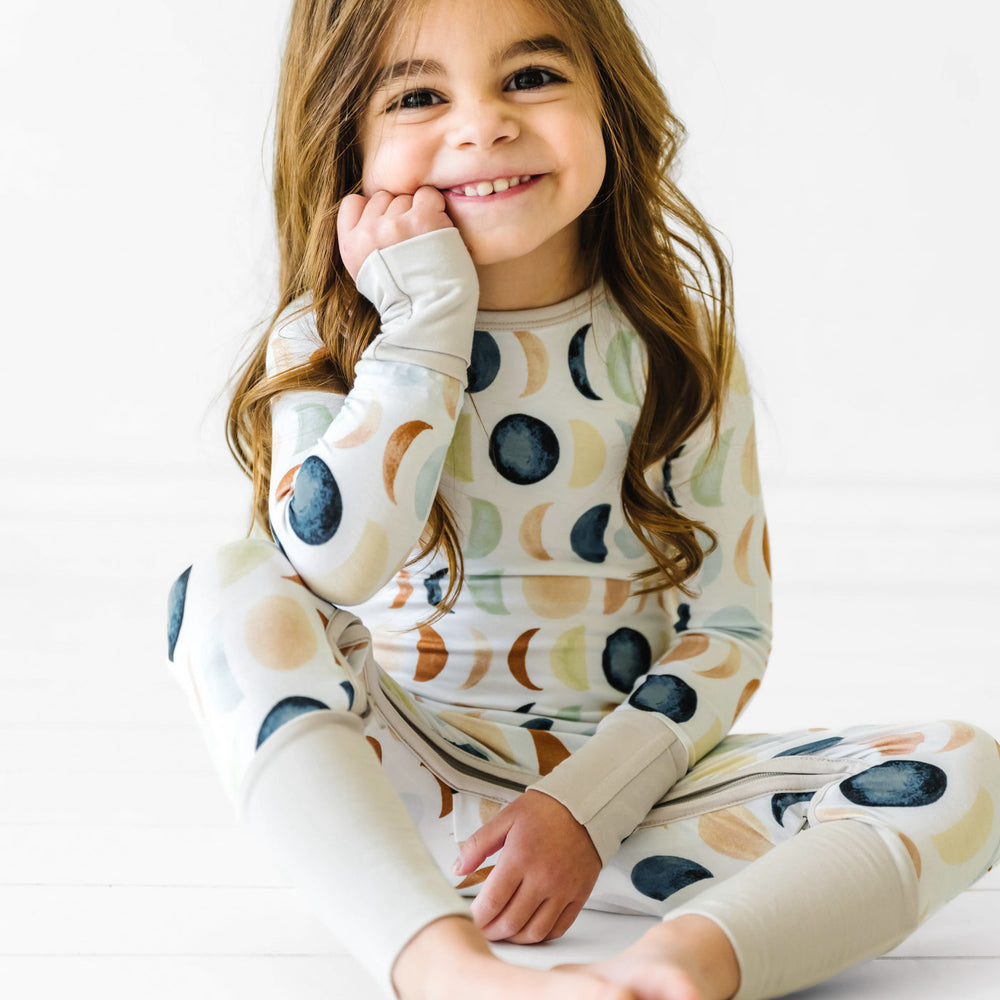 toddler sitting wearing a Luna Neutral crescent zippy