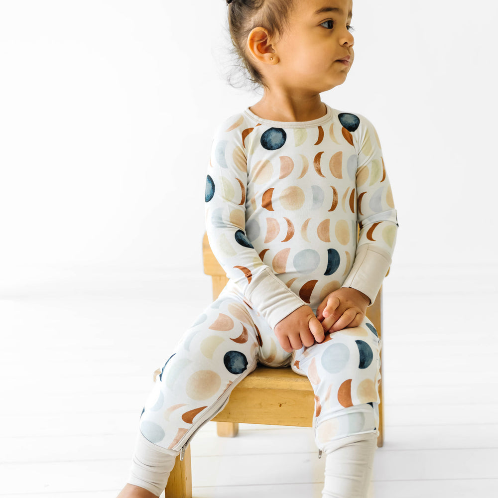 Toddler sitting on a chair wearing a Luna Neutral crescent zippy