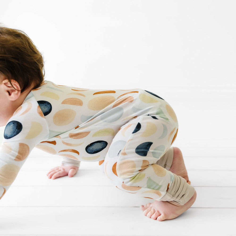 Child crawling wearing a Luna Neutral crescent zippy