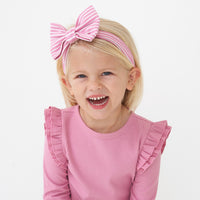 Close up image of a child wearing a Garden Rose Stripe luxe bow headband  paired with a ribbed Garden Rose flutter tee