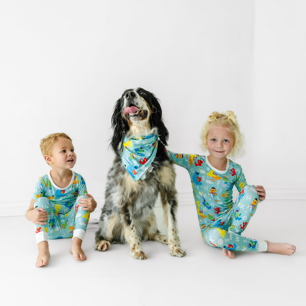Two children and a dog wearing matching Spelling with Sesame Street pajamas and pet bandana