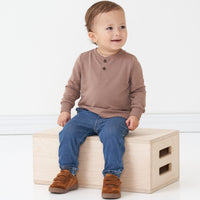 Child sitting on a box wearing a Light Cocoa henley tee