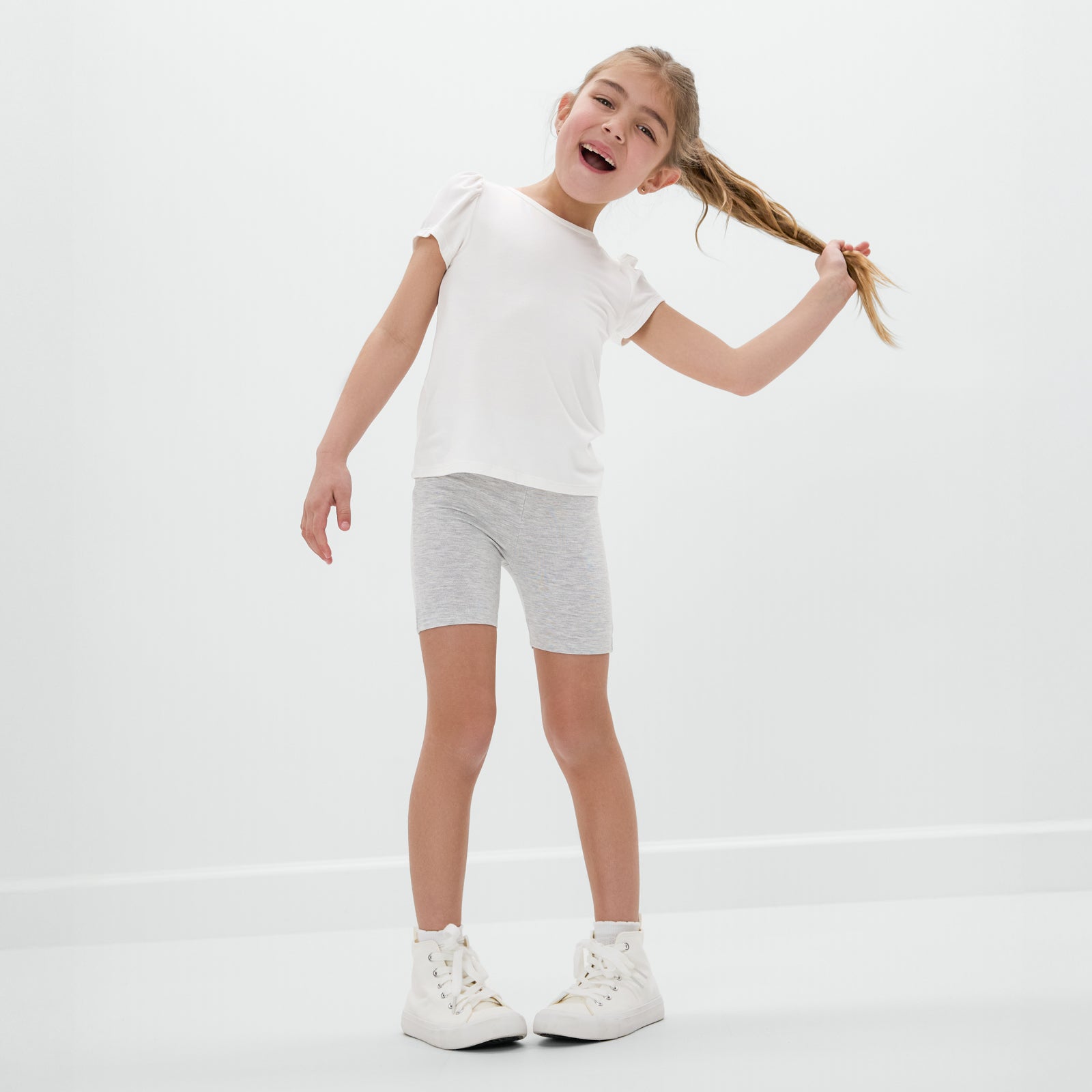 Posing child wearing the Light Heather Gray Bike Shorts with a white bamboo tee