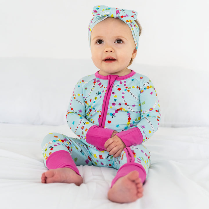 Sitting child wearing the Friends Forever Zippy and matching luxe bow headband