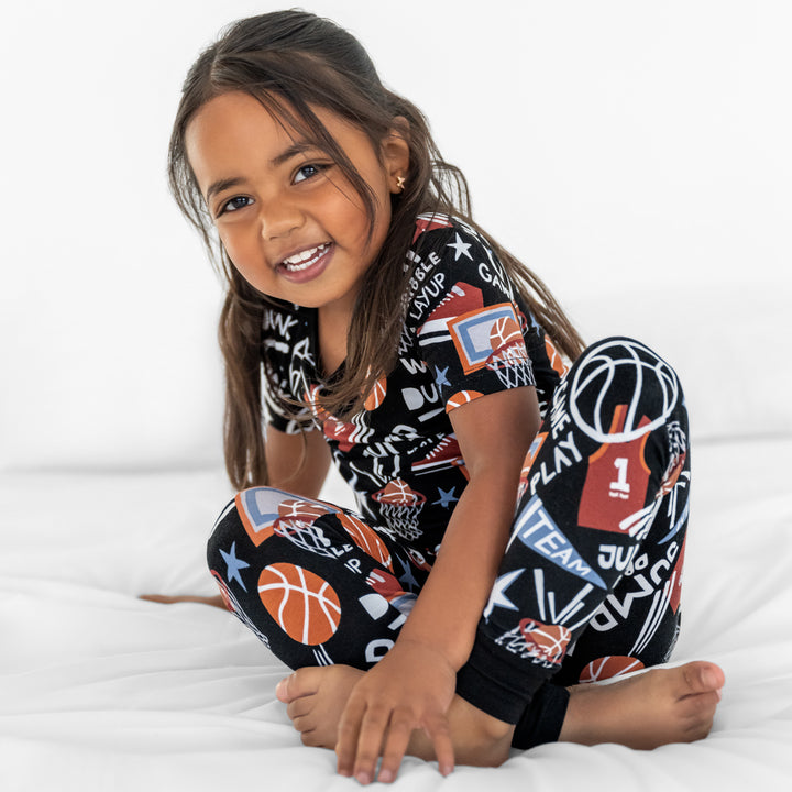 Child sitting in the Black Slam Dunk two-piece pajama set