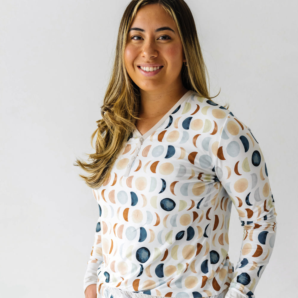 Cropped image of a woman wearing Luna Neutral printed pajama top and pajama pants. This print features phases of the moon in the sweetest shades of creams, tans, and navy watercolor in an all over repeat pattern.