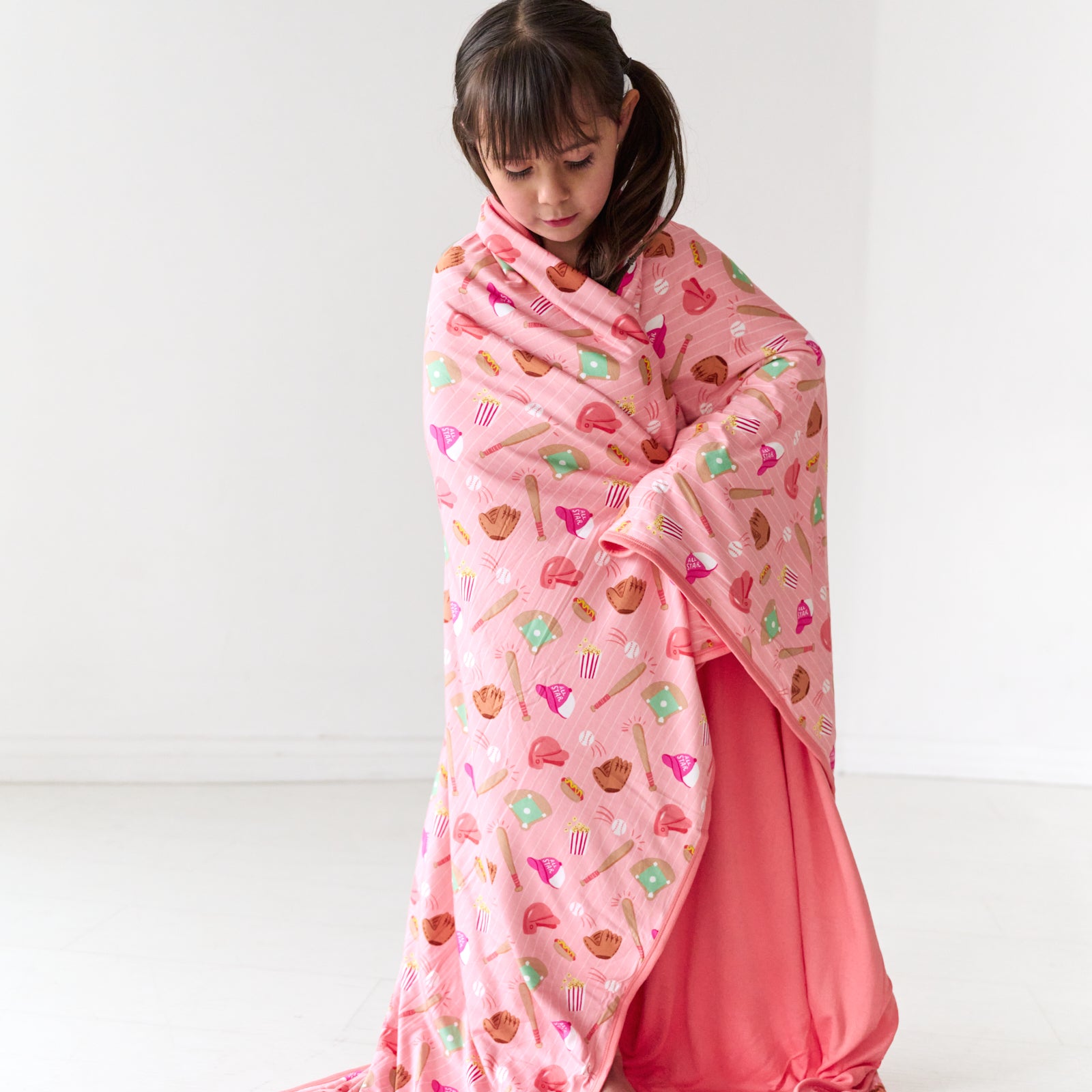 Standing child wrapped up in a Pink All Stars bamboo large cloud blanket