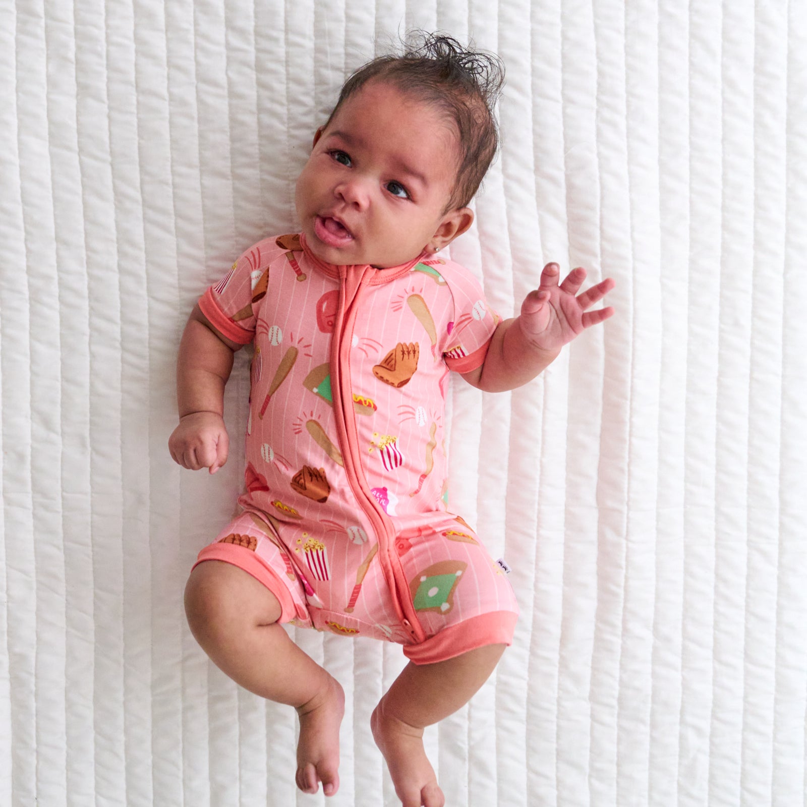 Child laying on a bed wearing a Pink All Stars bamboo shorty zippy