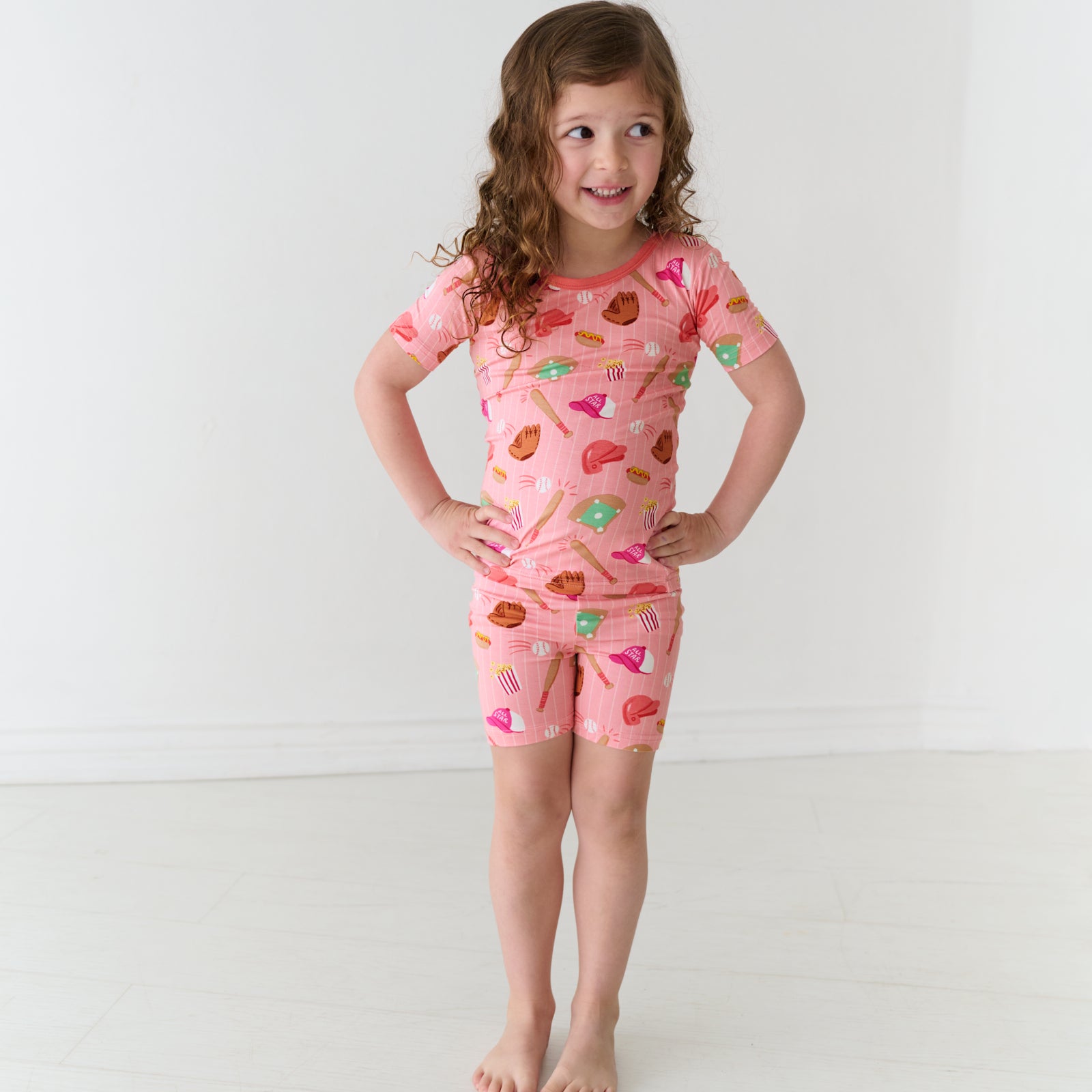 Child posing wearing a Pink All Stars two-piece short sleeve and shorts bamboo pajama set