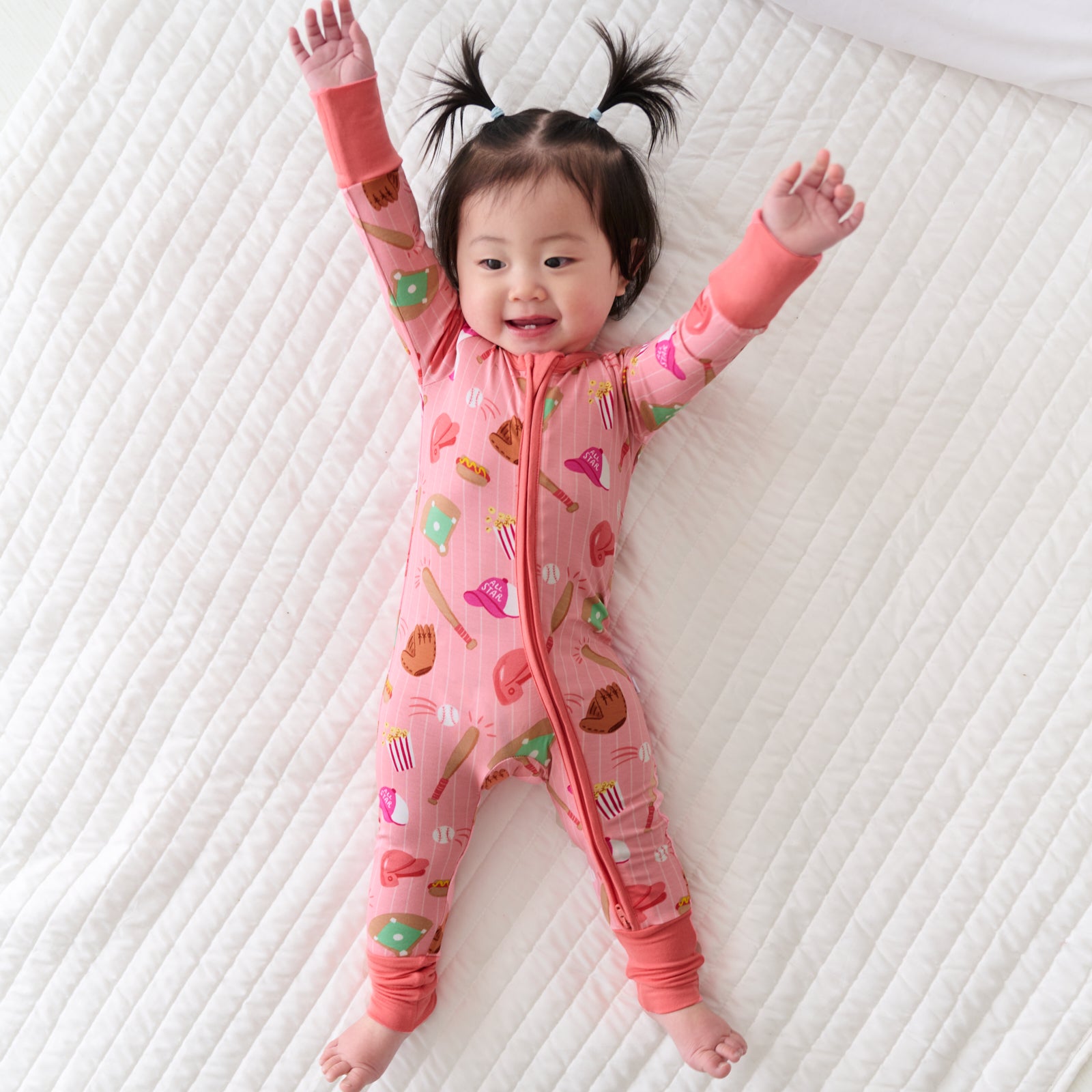 Child laying on a bed wearing a Pink All Stars bamboo zippy