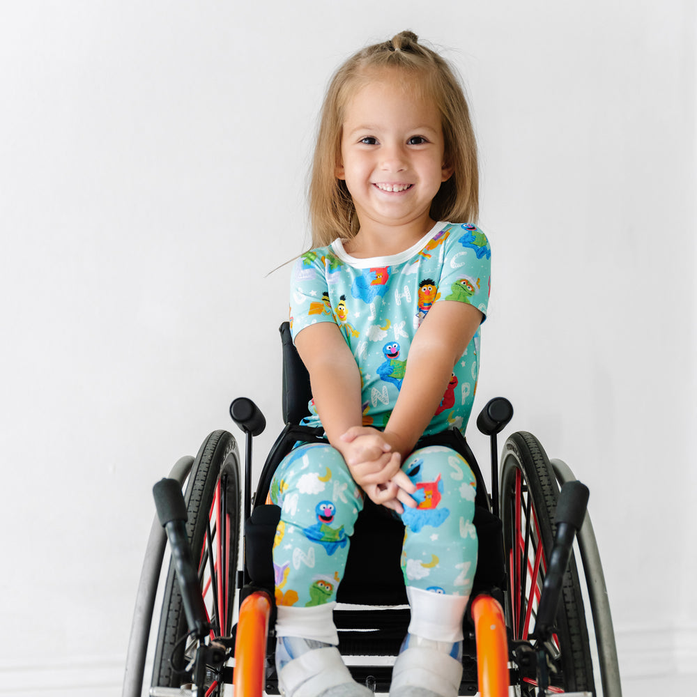 Child in a wheelchair wearing a Spelling with Sesame Street two piece short sleeve pajama set
