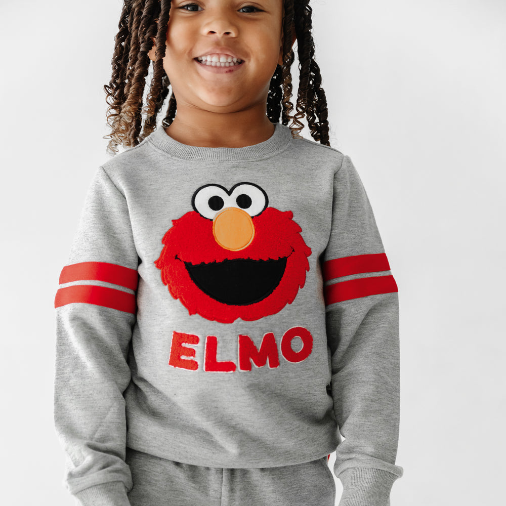 Close up image of a child wearing a Sesame Street Elmo crewneck sweatshirt and jogger set