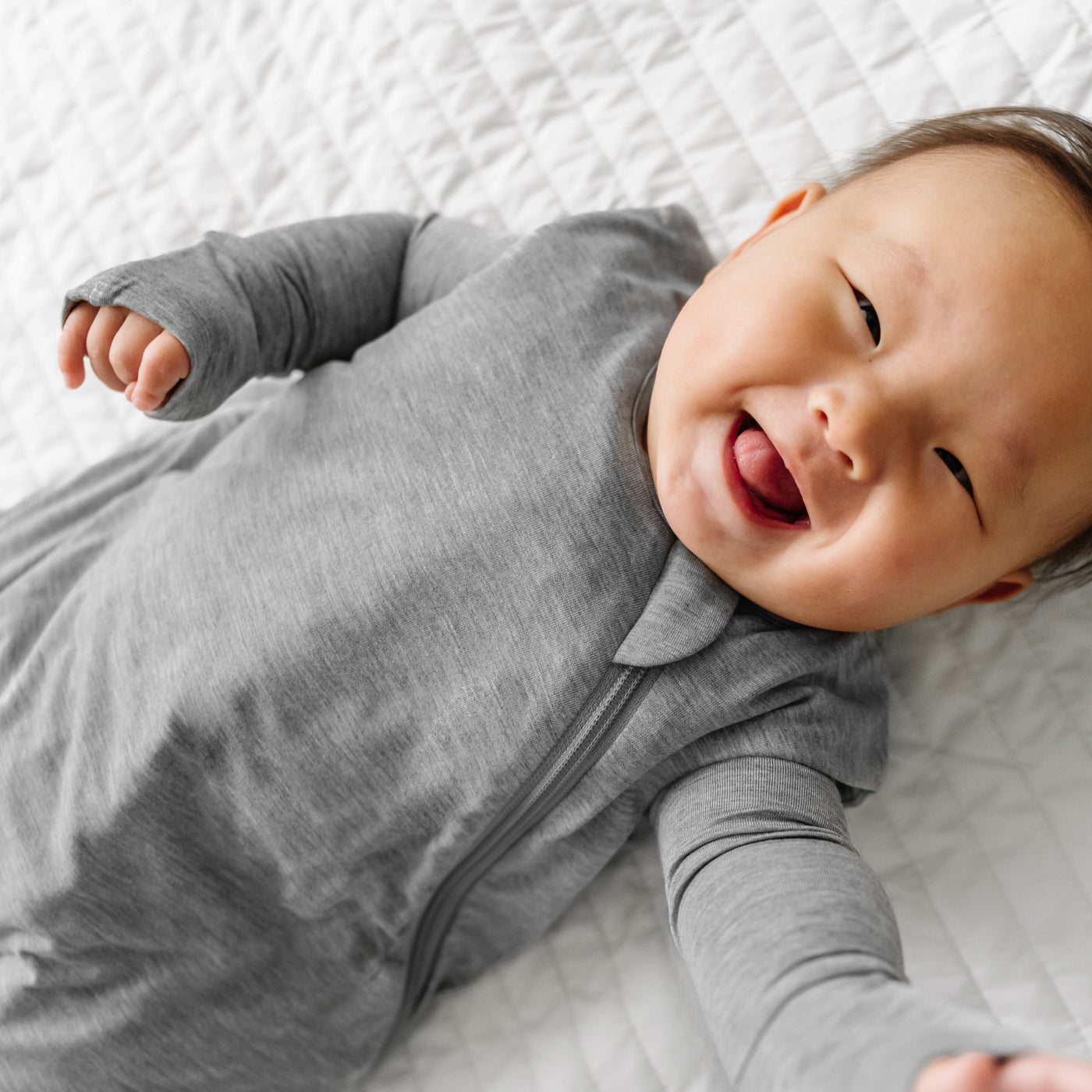 Close up image of a child wearing a Heather Gray Sleepy Bag and matching zippy