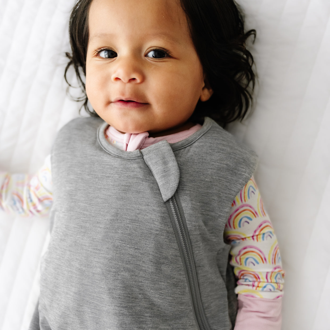 Close up image of a child wearing a Heather Gray Sleepy Bag and coordinating zippy