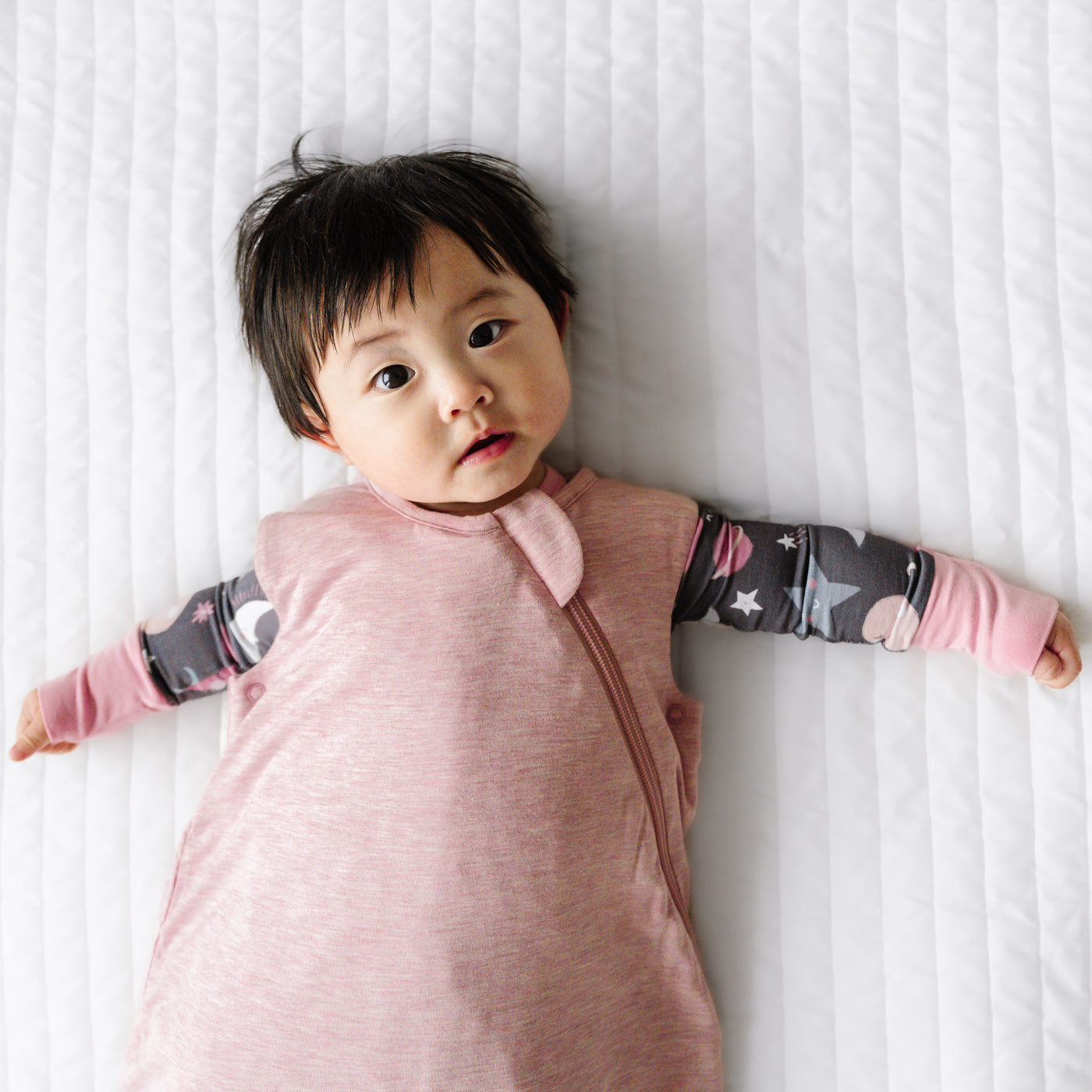 Close up image of a child wearing a Heather Mauve sleepy bag and coordinating zippy
