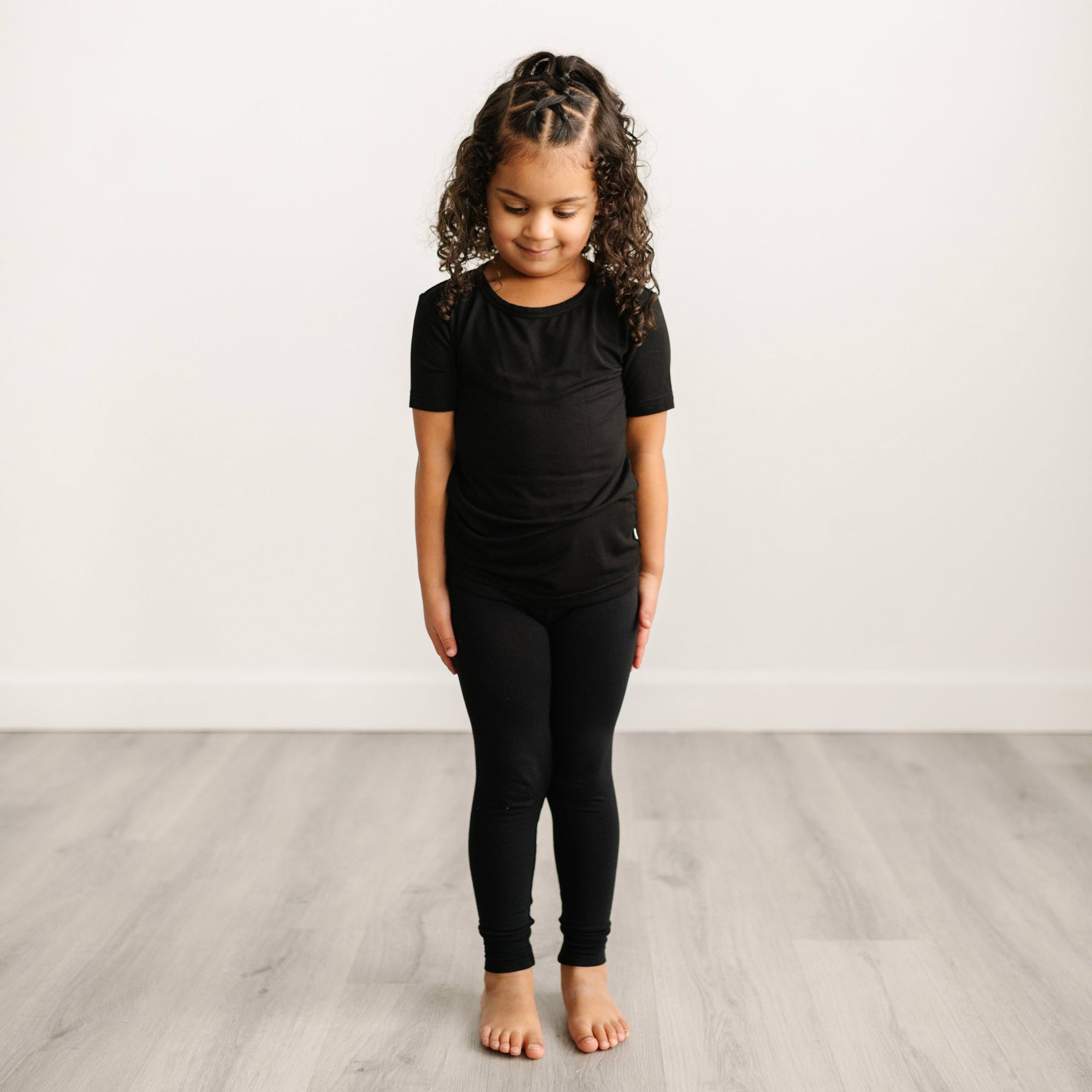 Image of little girl modeling a solid black short sleeve pajama set.