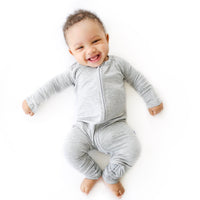 Image of baby boy wearing zip up romper in heather gray.