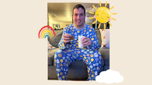 David Isaacman sitting on a couch wearing Blue Cookies & Milk pajamas and holding cookies and a glass of milk