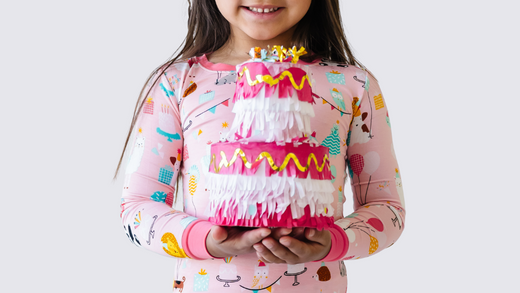 child holding a cake decoration in pink party animals birthday print