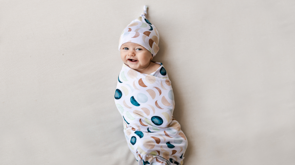 infant in luna neutral swaddle and hat set