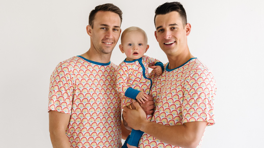 family of three wearing matching rainbow pajamas