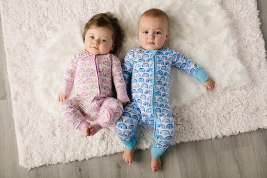 two infants wearing coordinating rainbow zippies