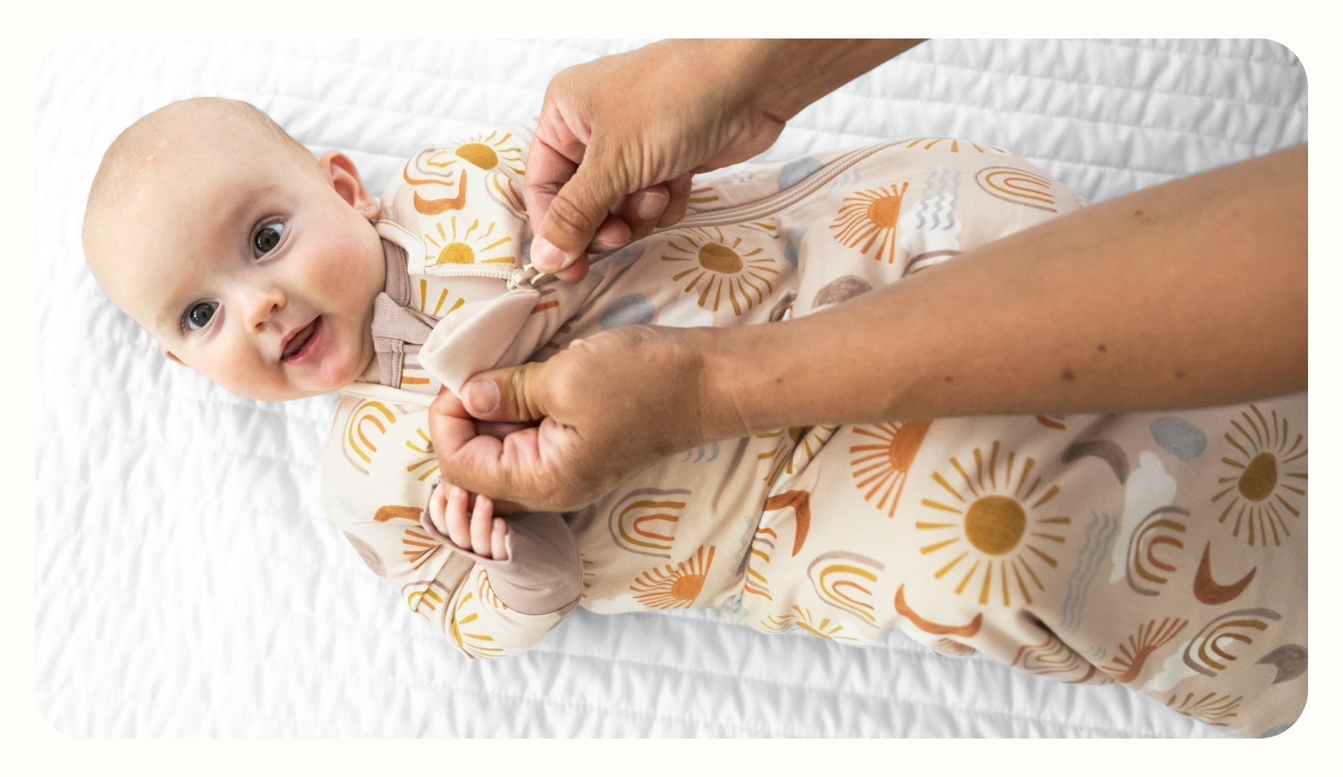 Infant lying on a blanket wearing a Desert Sunrise Sleepy Bag and Zippy