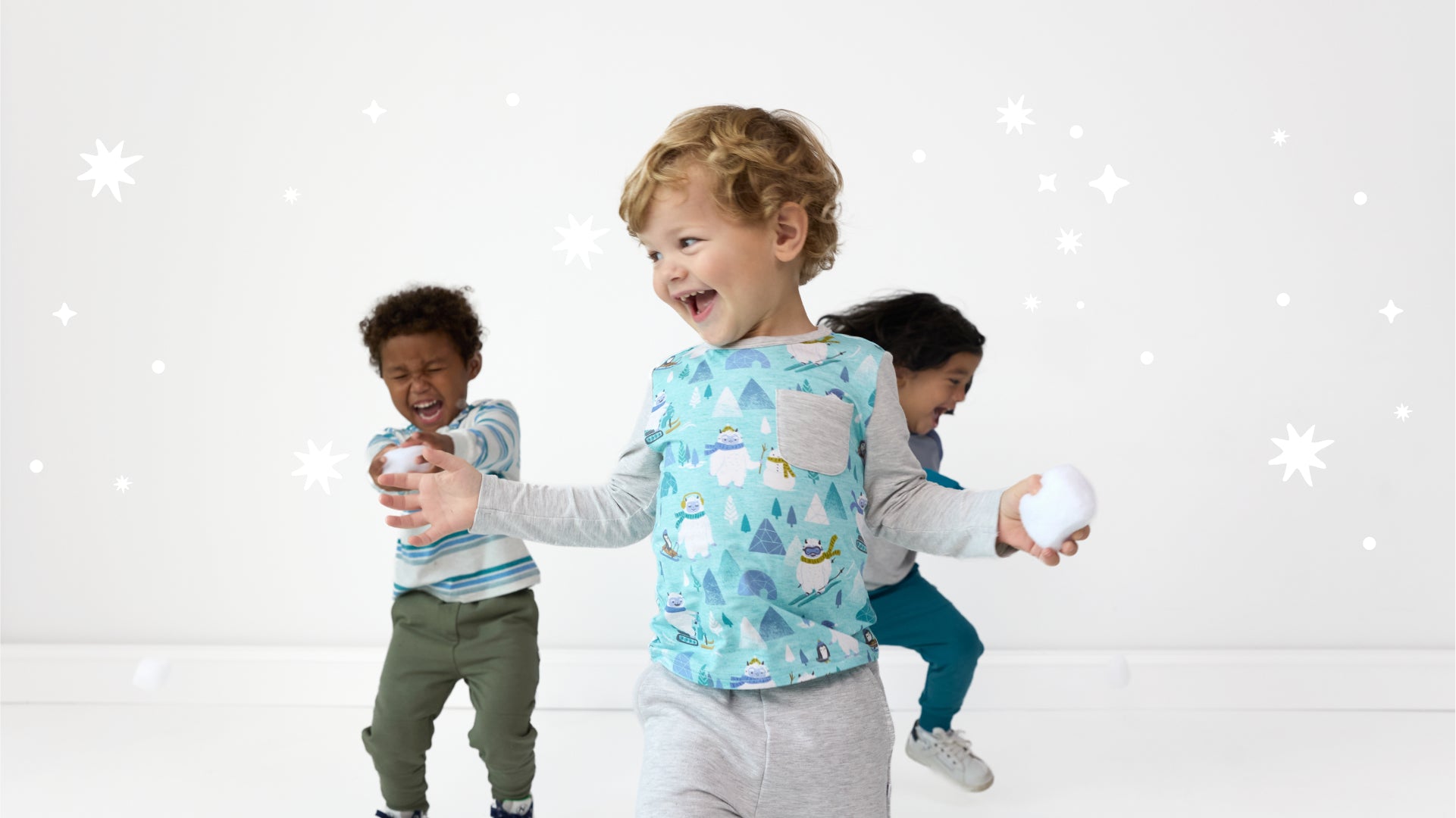 Image of three children throwing snowballs, wearing Little Sleepies Winter Play Collection clothing