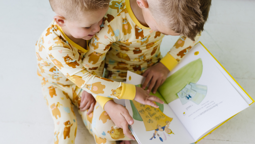 two children wearing matching pajamas and reading a book together