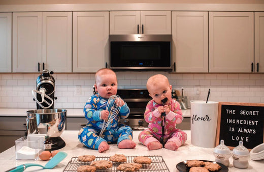 two toddlers sitting in front of freshly baked cookies and wearing matching Cookies & Milk pajamas