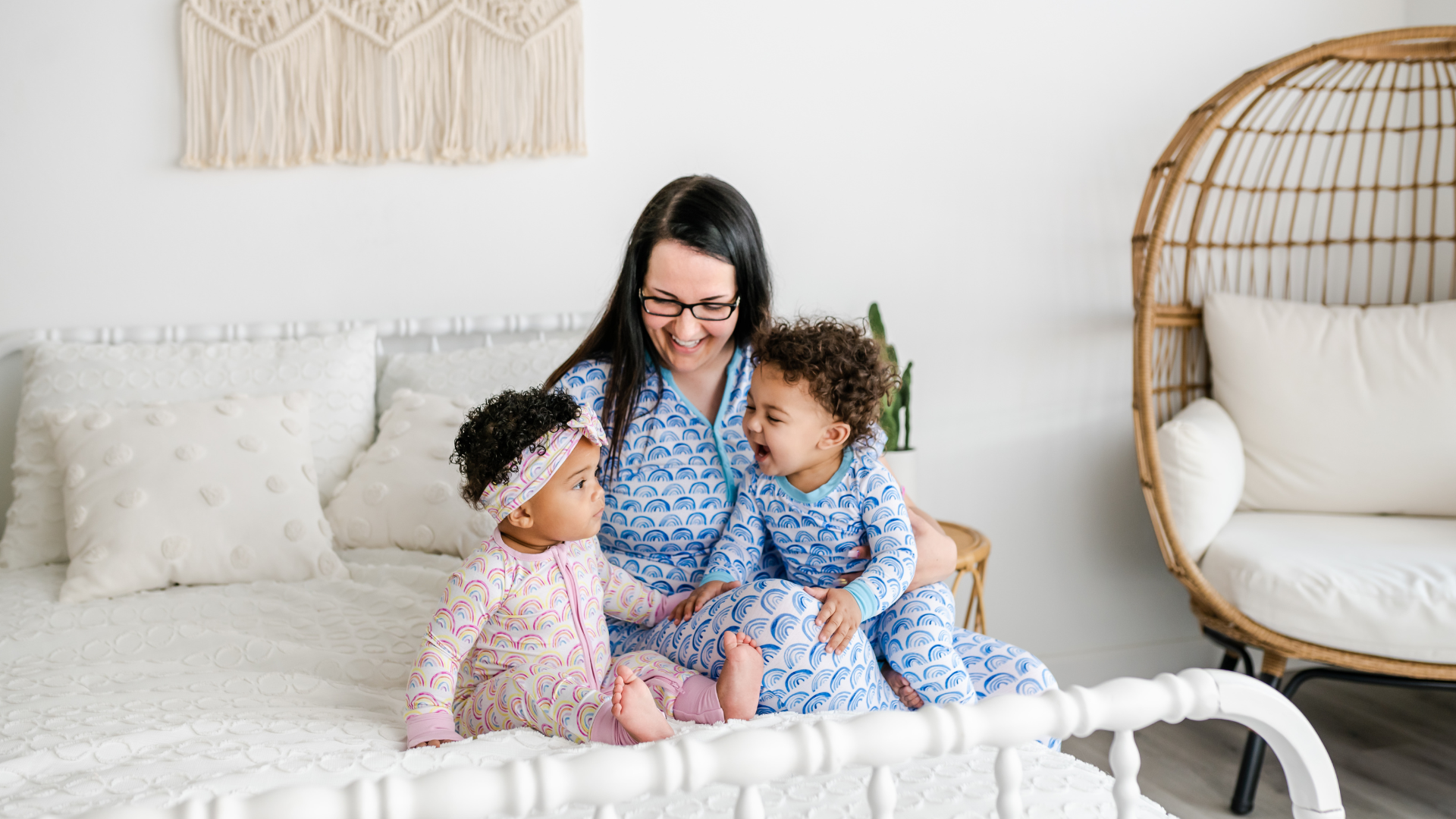 mom with two children wearing matching rainbow pajamas