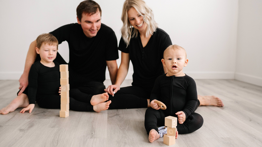 family of four playing with blocks and wearing matching black pajamas