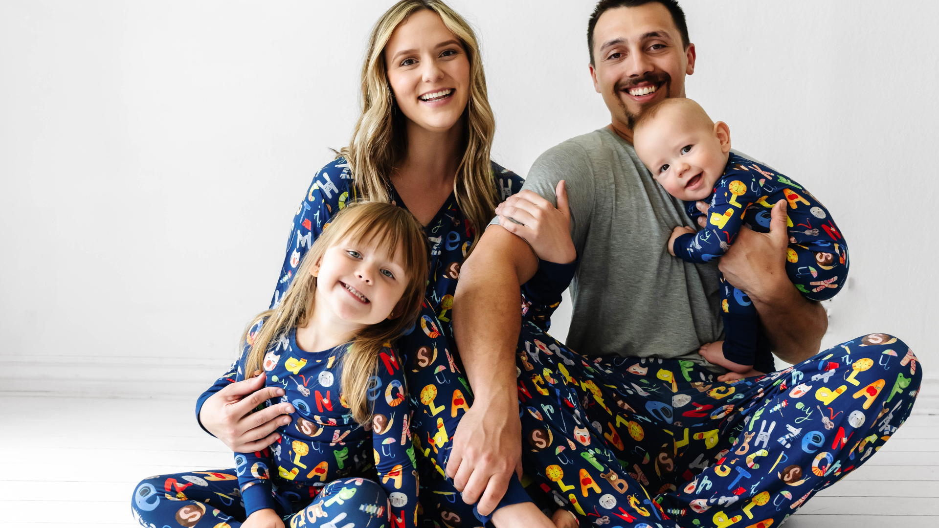 Family of four wearing matching Alphabet Friends pajamas