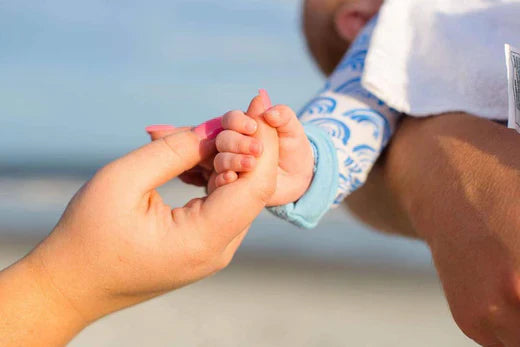 mother holding the hand of an infant wearing rainbow pajamas