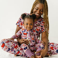 Child in two-piece long sleeve and pants pajama set in Butterfly Kisses.