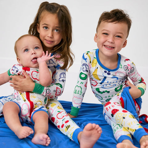 Three children wearing matching Coloring Crew pajamas