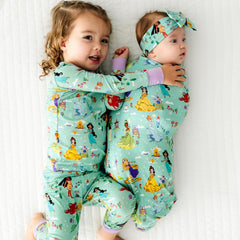 Two children laying on a blanket wearing matching Disney Princess Dreams pajamas and swaddle set