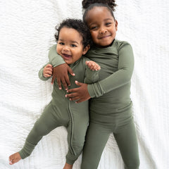 two children cuddling wearing matching olive pjs