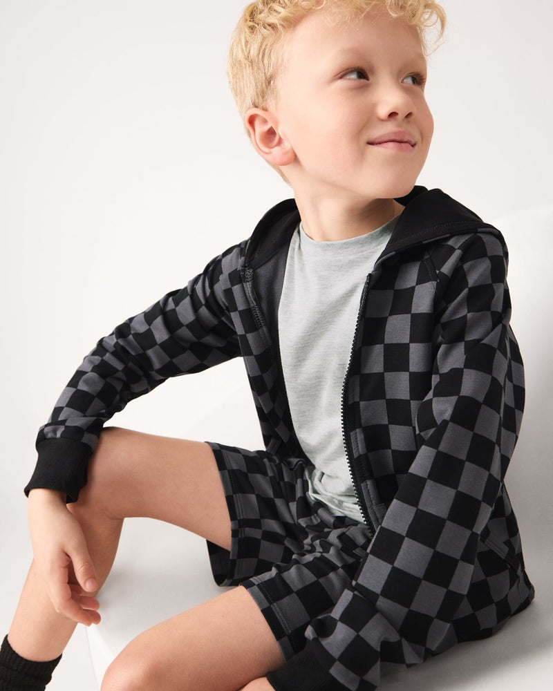 Sitting boy wearing the Monochrome Checks Zip Hoodie and Shorts
