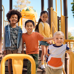 four children playing on a playground wearing Play by Little Sleepies outfits