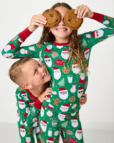 Two kids wearing matching cookies for santa holiday pajamas