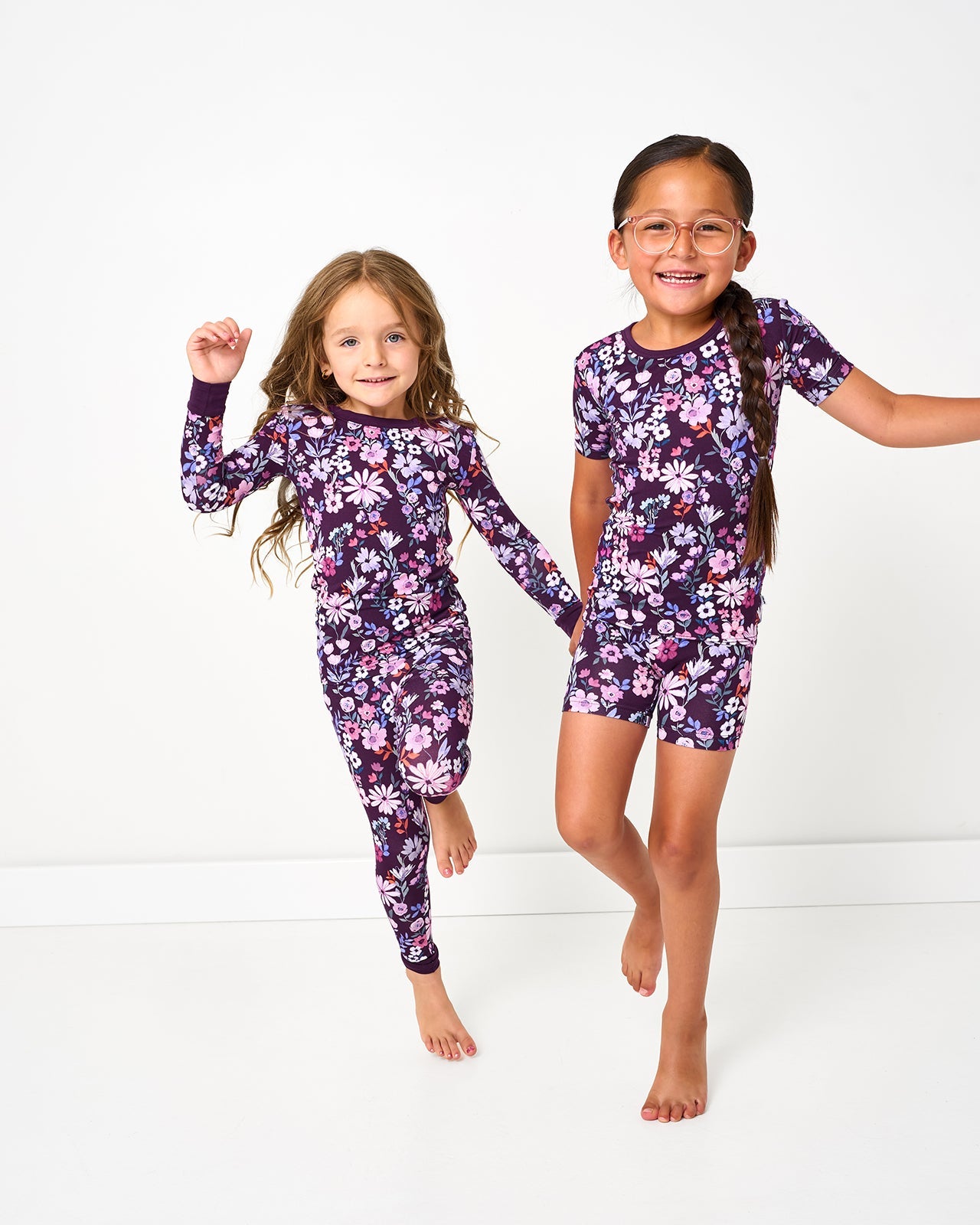 Two girls wearing violet meadow floral girls pajamas