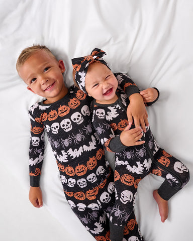 Two children wearing matching Hallows Eve halloween pajamas pajamas