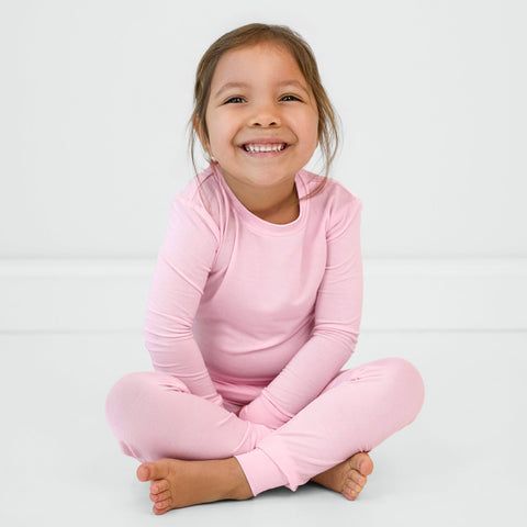Sitting child wearing the Soft Pink two-piece pajama set
